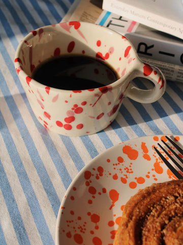 Romi ceramic mug with red splatter pattern handmade coffee cup with pastry and matching plate