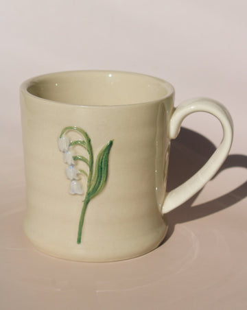 Bellis ceramic mug with lily of the valley motif, handmade floral coffee cup for cozy morning rituals.