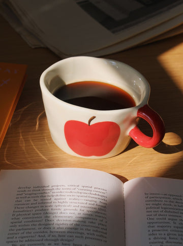 Pom ceramic mug with red apple design, handmade coffee cup for cozy mornings and everyday use