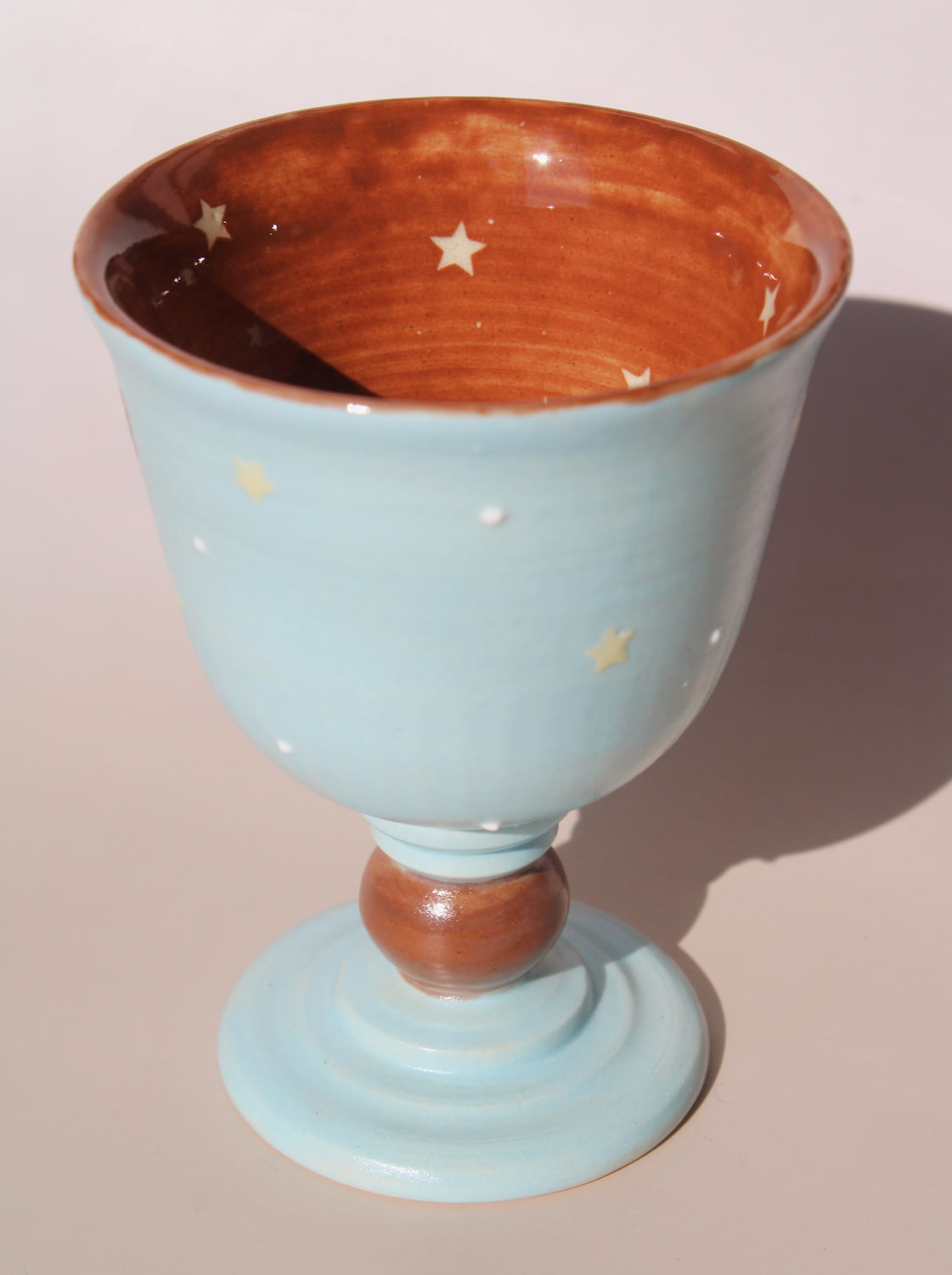 Hand-painted ceramic goblet with running horse motif and star details on light blue glaze.