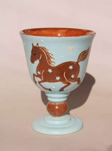 Hand-painted ceramic goblet with running horse motif and star details on light blue glaze.