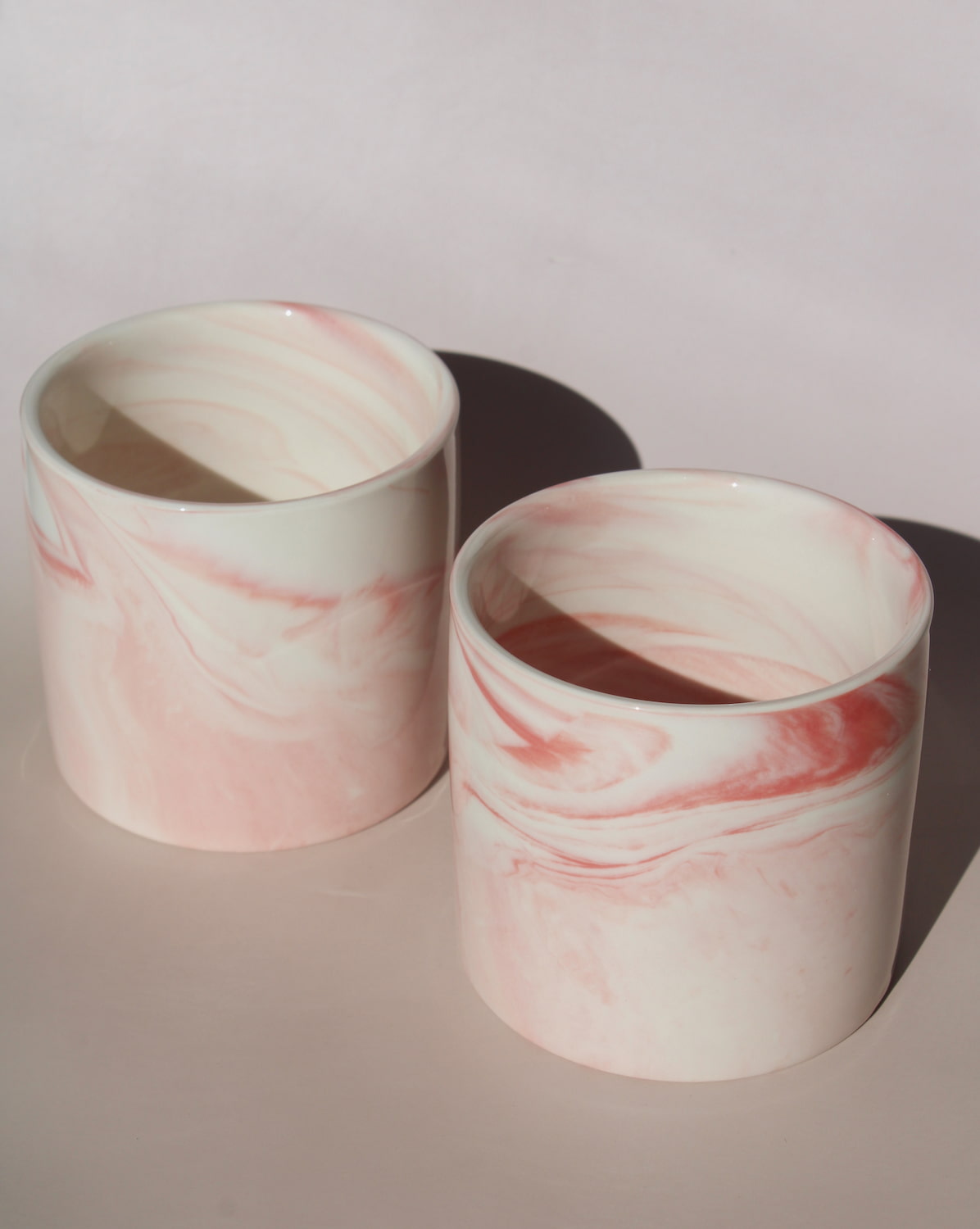Two Blush ceramic cups with pink marble swirl glaze, handmade stoneware cups for modern tableware.