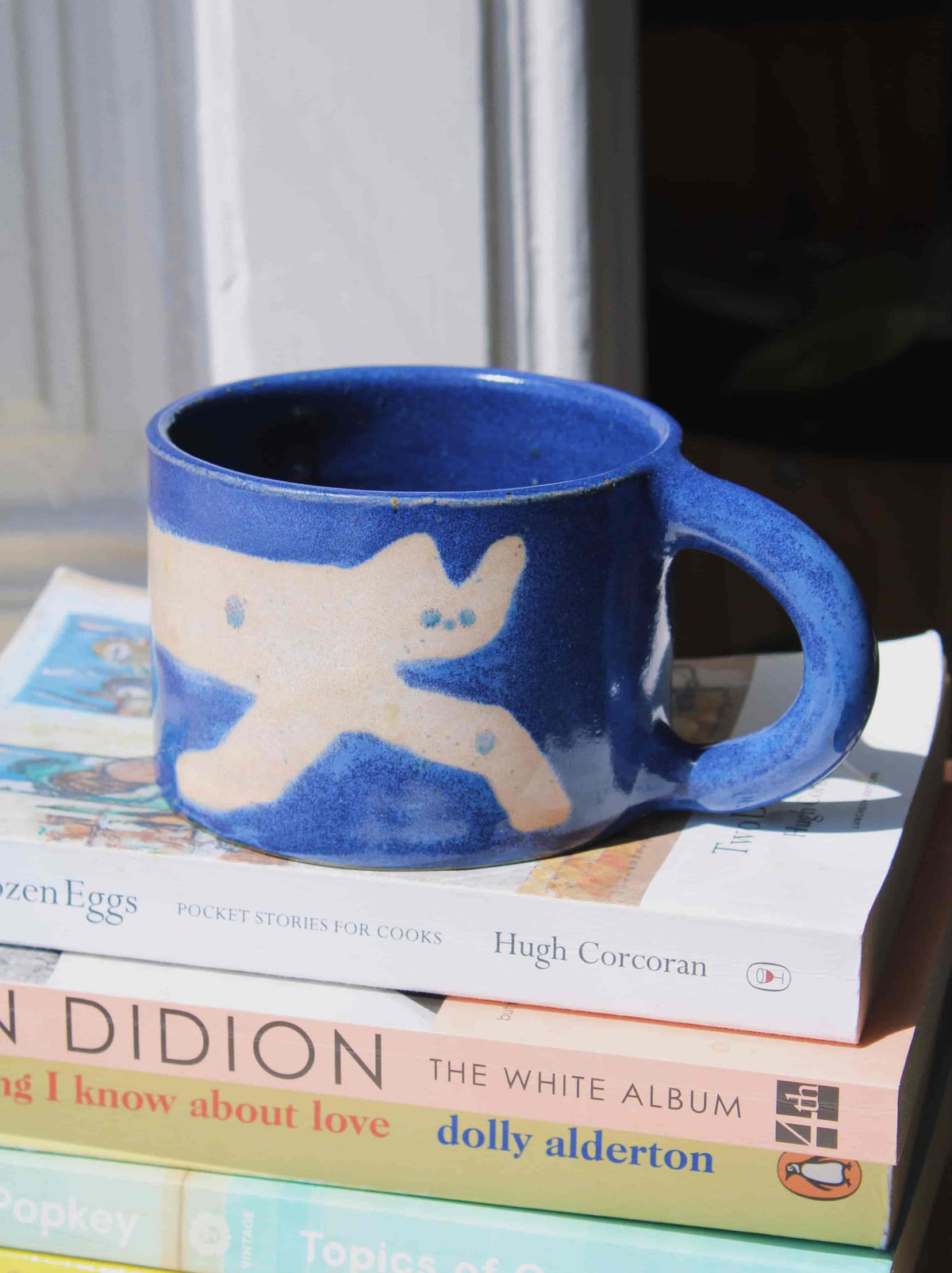 Moonmilk Cat Ceramic Mug by Marta Shurpakova – handmade blue ceramic mug with a playful cat design in a cosy home setting