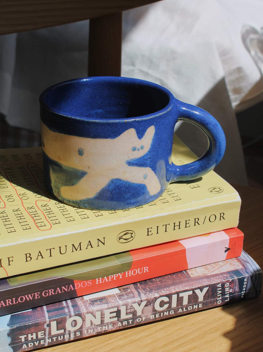 Moonmilk Cat Ceramic Mug by Marta Shurpakova – handmade blue ceramic mug with a playful cat design in a cosy home setting