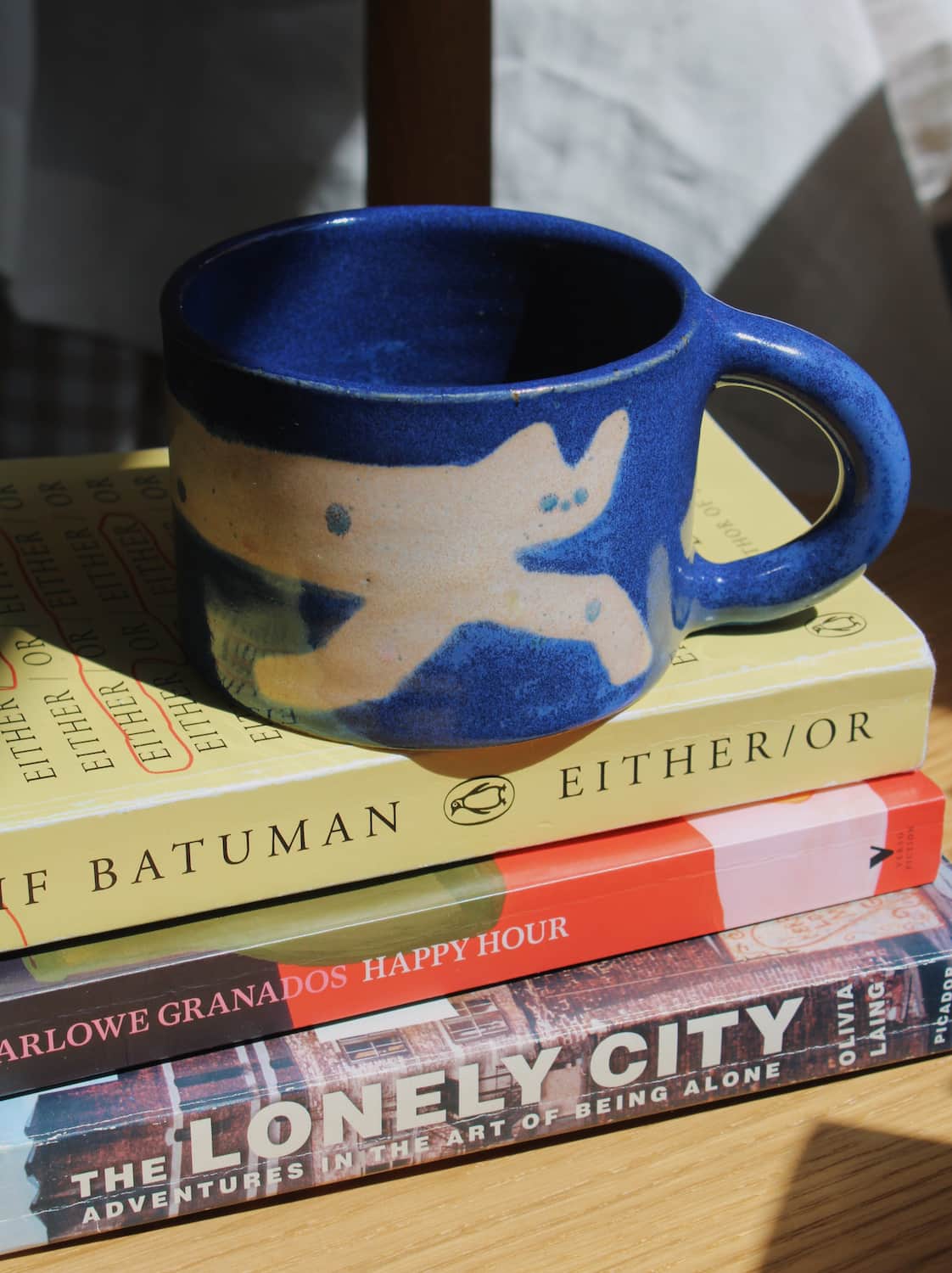 Moonmilk Cat Ceramic Mug by Marta Shurpakova – handmade blue ceramic mug with a playful cat design in a cosy home setting