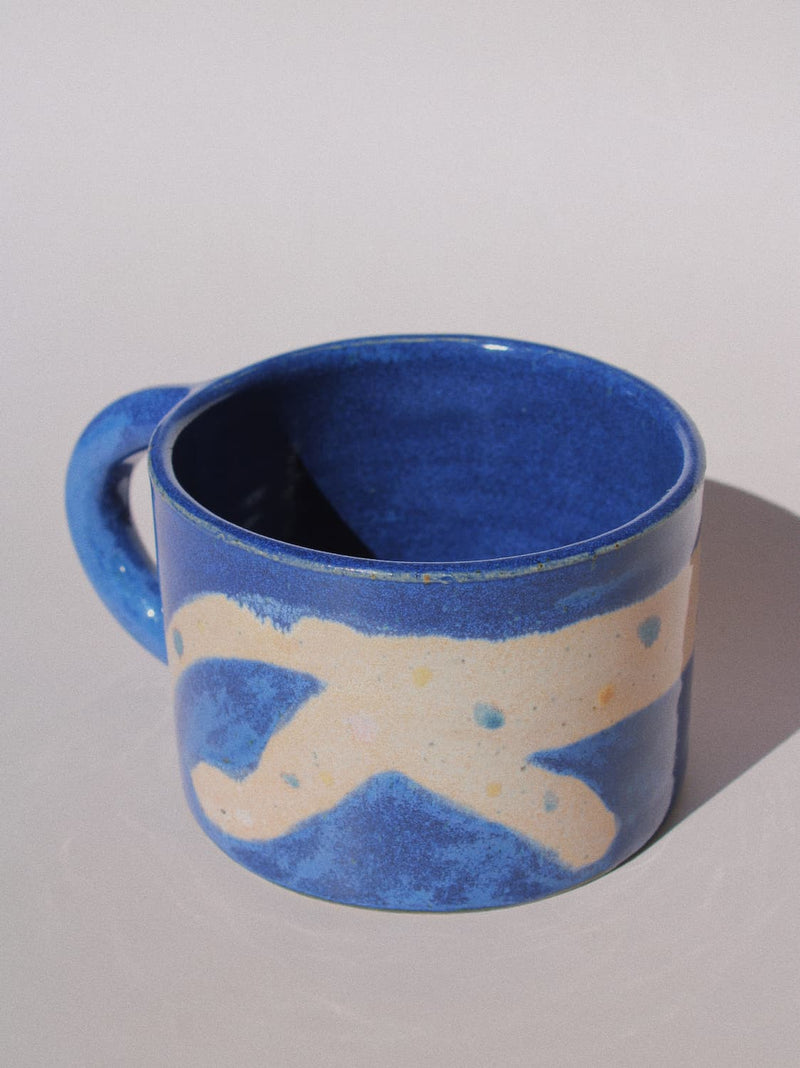 Moonmilk Cat Ceramic Mug by Marta Shurpakova – handmade blue ceramic mug with a playful cat design on a pink background