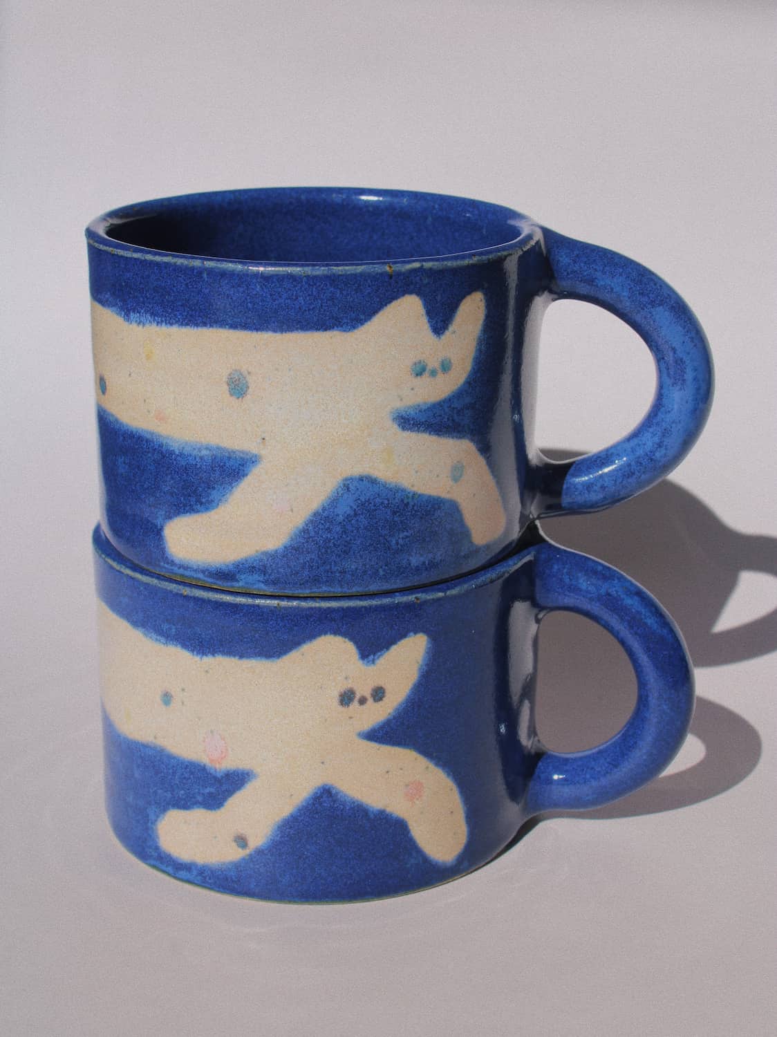 Moonmilk Cat Ceramic Mug by Marta Shurpakova – handmade blue ceramic mug with a playful cat design on a pink background