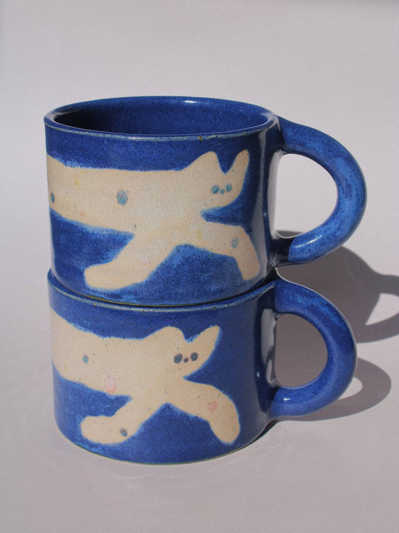 Moonmilk Cat Ceramic Mug by Marta Shurpakova – handmade blue ceramic mug with a playful cat design on a pink background