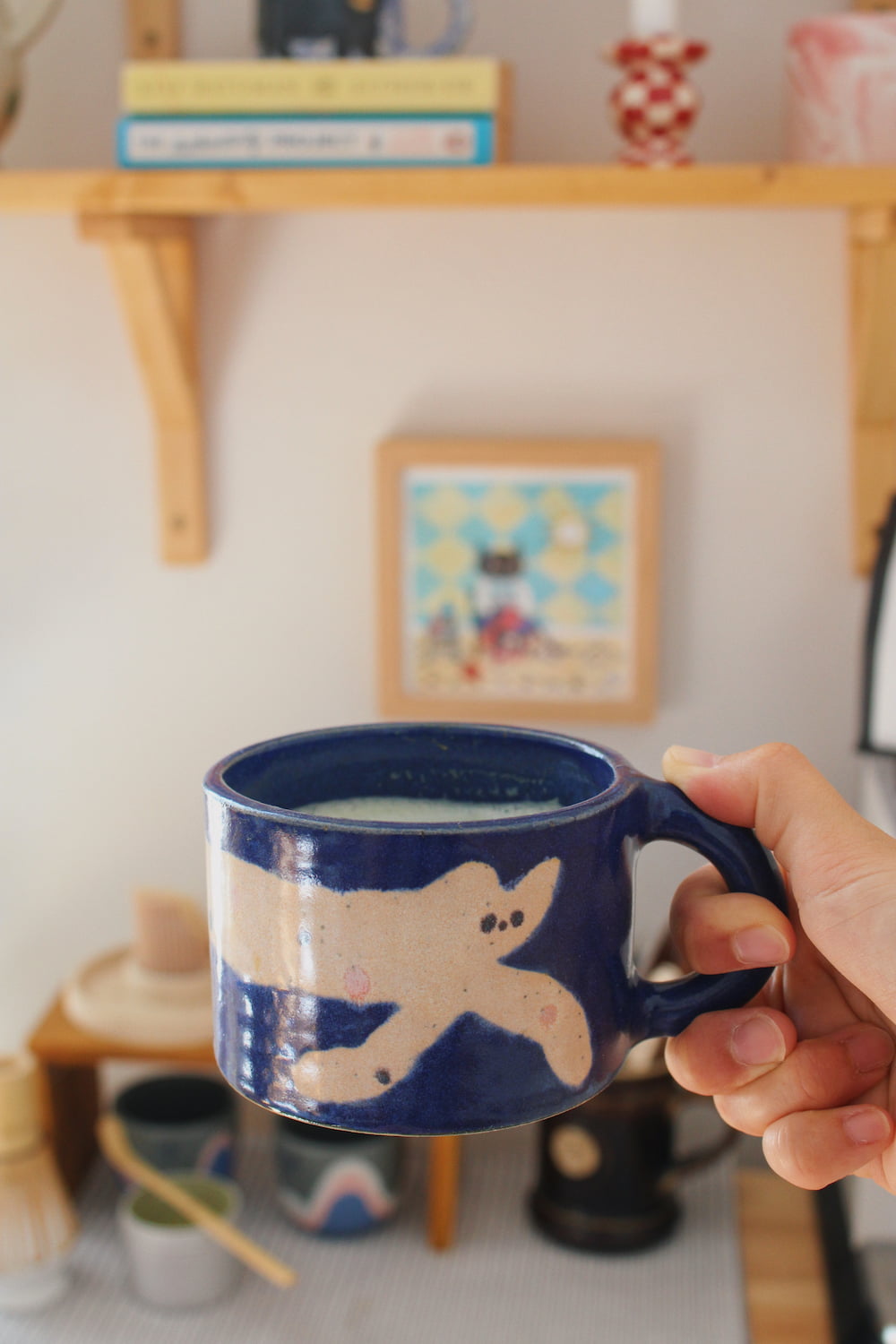 Moonmilk Cat Ceramic Mug by Marta Shurpakova – handmade blue ceramic mug with a playful cat design in a cosy home setting