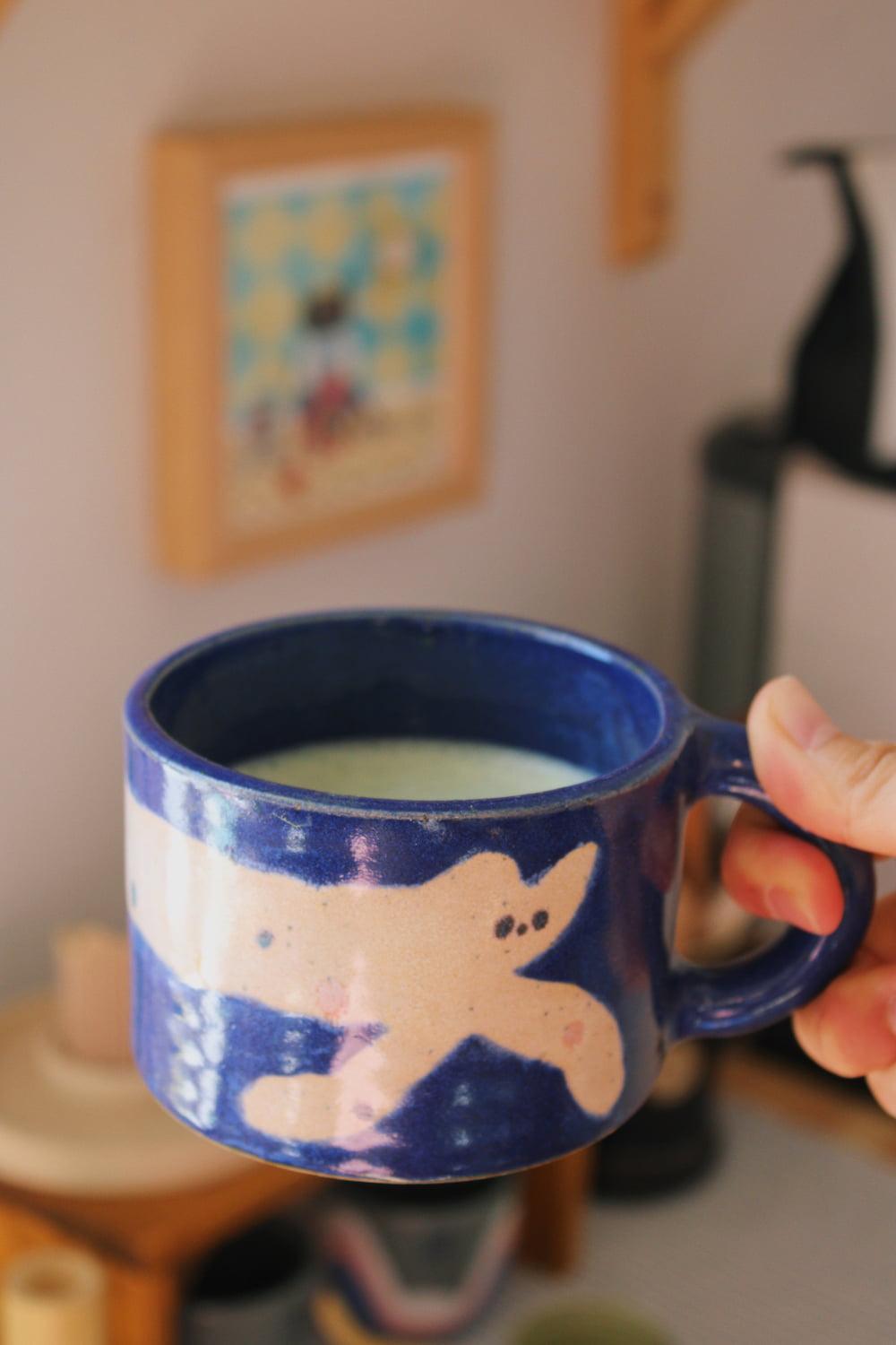 Moonmilk Cat Ceramic Mug by Marta Shurpakova – handmade blue ceramic mug with a playful cat design in a cosy home setting