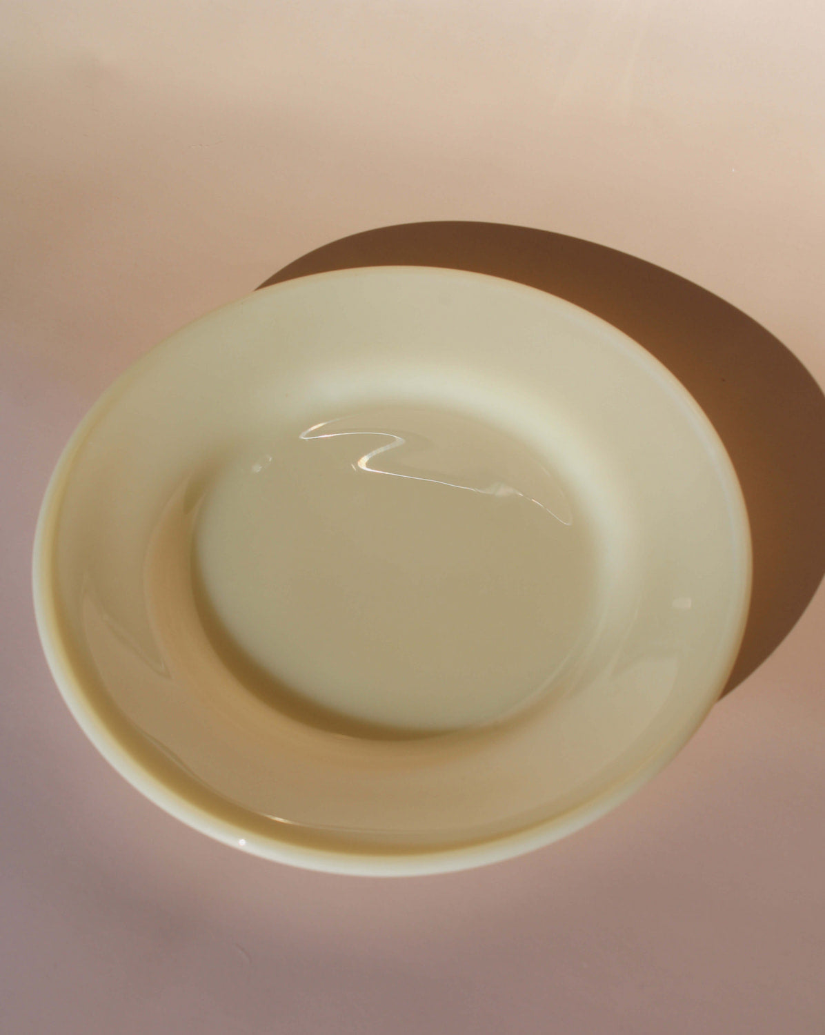 Plain yellow plate on a light pink background