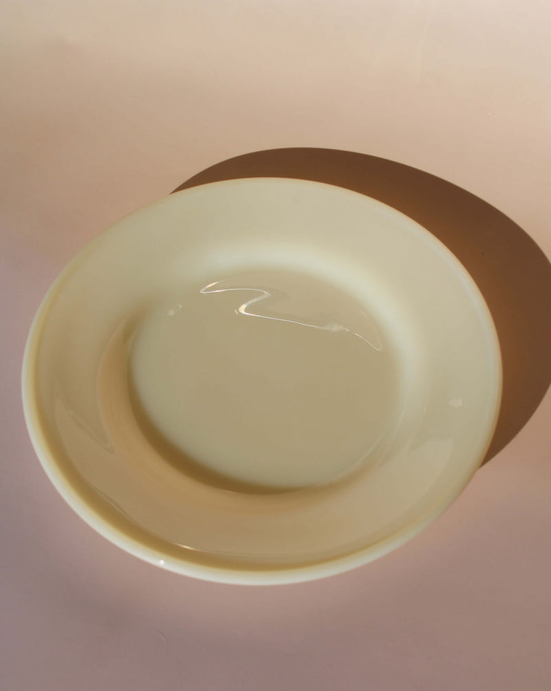 Plain yellow plate on a light pink background