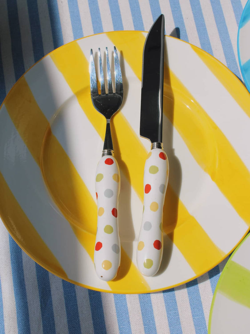Etta Ceramic Plate in yellow with bold stripe pattern, styled with a sesame pastry and the Confetti Cutlery Set fork on a blue striped surface