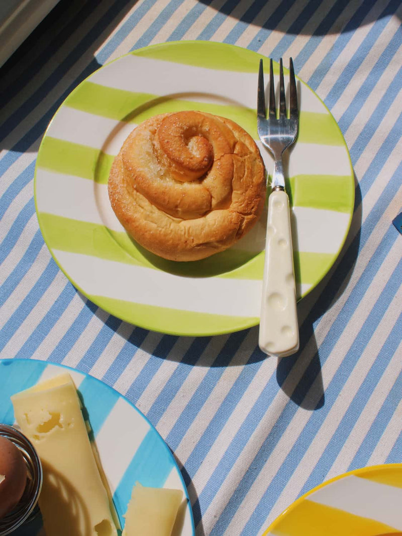 Olia Ceramic Plate in green with bold stripe pattern, styled with a cinnamon roll and fork