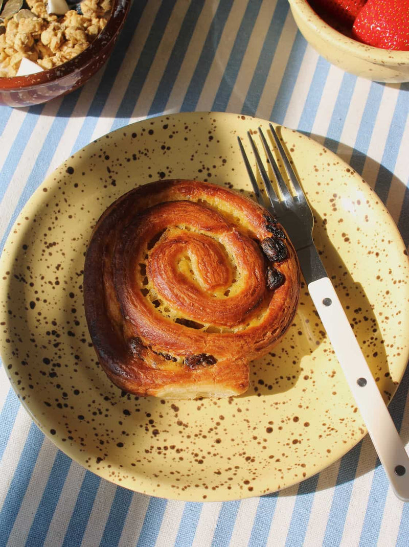Handmade Ocre ceramic plate with speckled finish styled with breakfast.