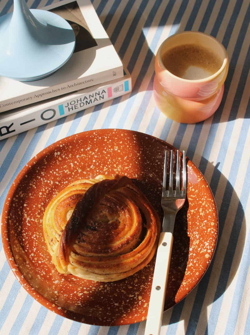 Speckled ceramic plate with croissant and coffee cup, warm-toned handmade tableware for breakfast setting