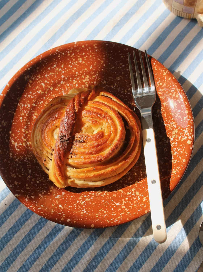 Handmade speckled ceramic plate with pastry and knife, rustic pottery plate for everyday dining