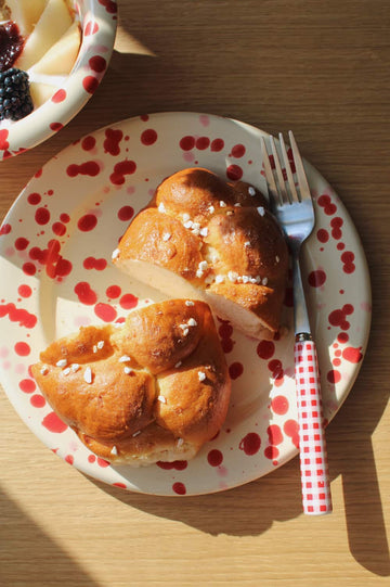 Dotty Ceramic Plate in cream with red speckled dot pattern, styled with a brioche 