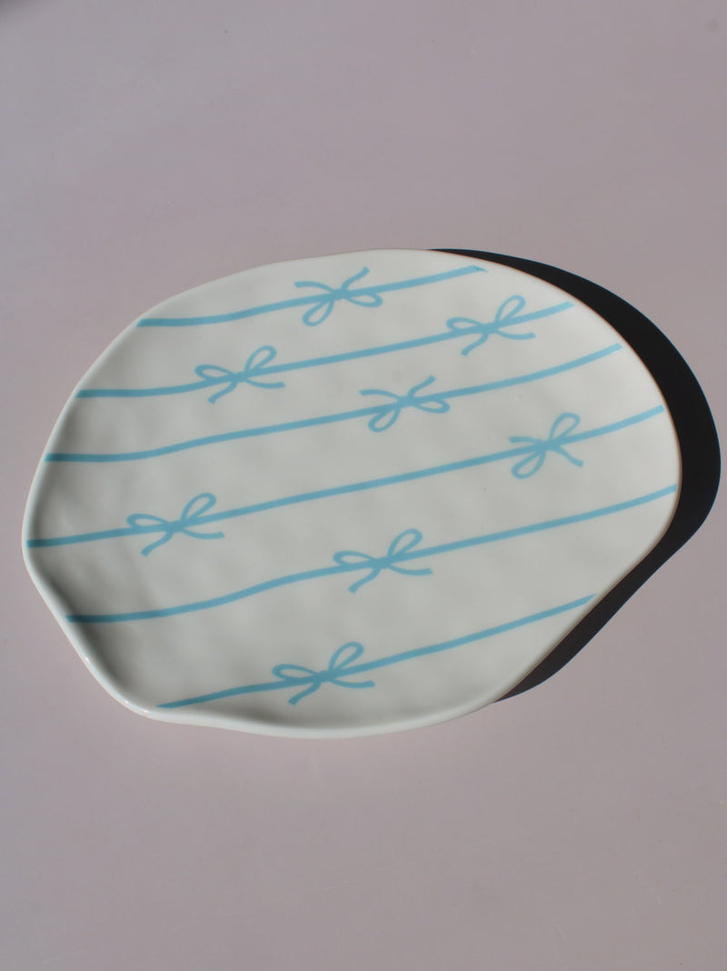 Rina Ceramic Plate with blue bow and ribbon line pattern, organic-shaped handmade ceramic plate top view