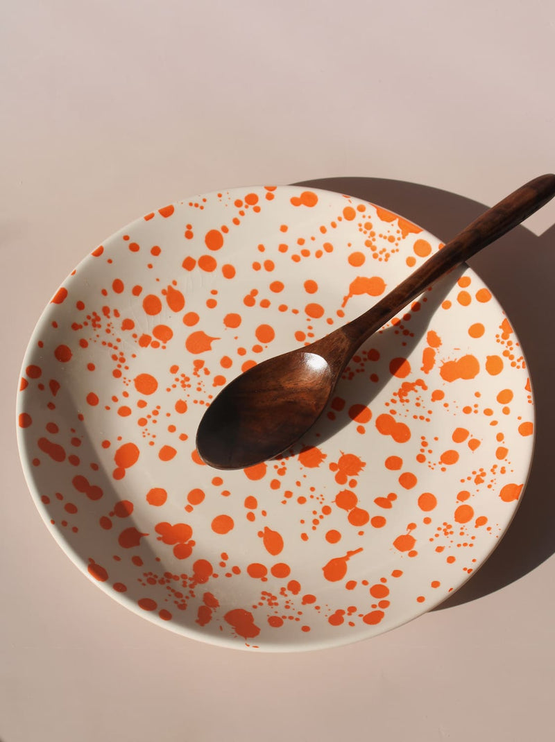 Orange splatter ceramic dinner plate with hand-applied speckled glaze pattern.