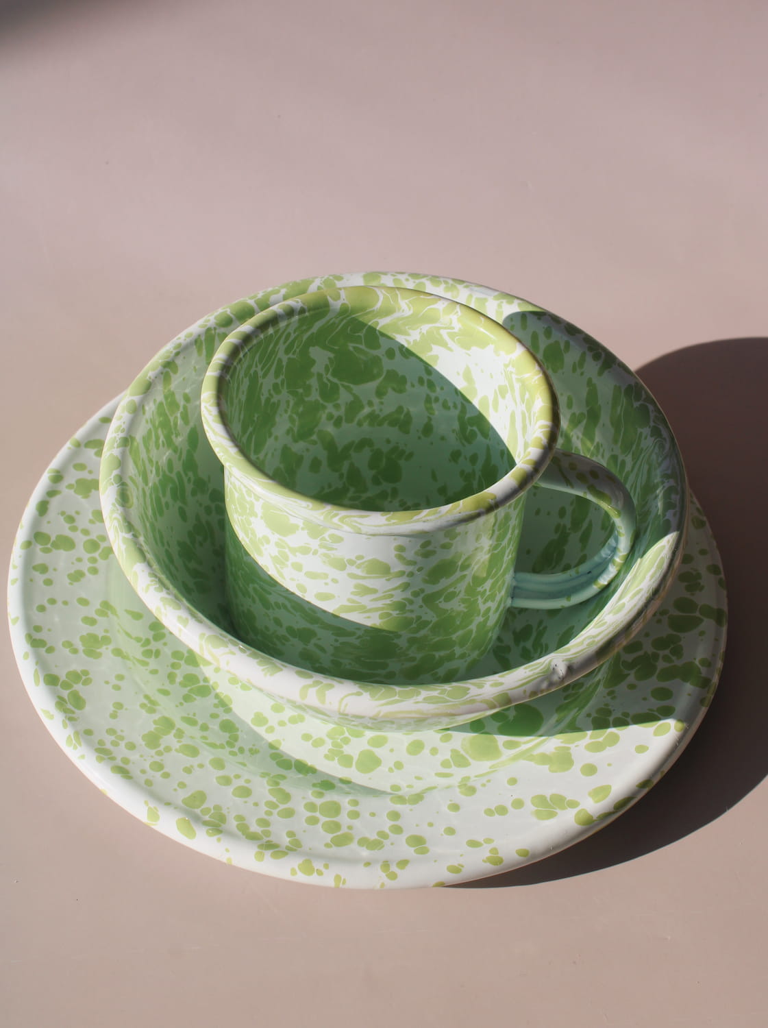 Green and white ceramic cup and saucer set on a beige background