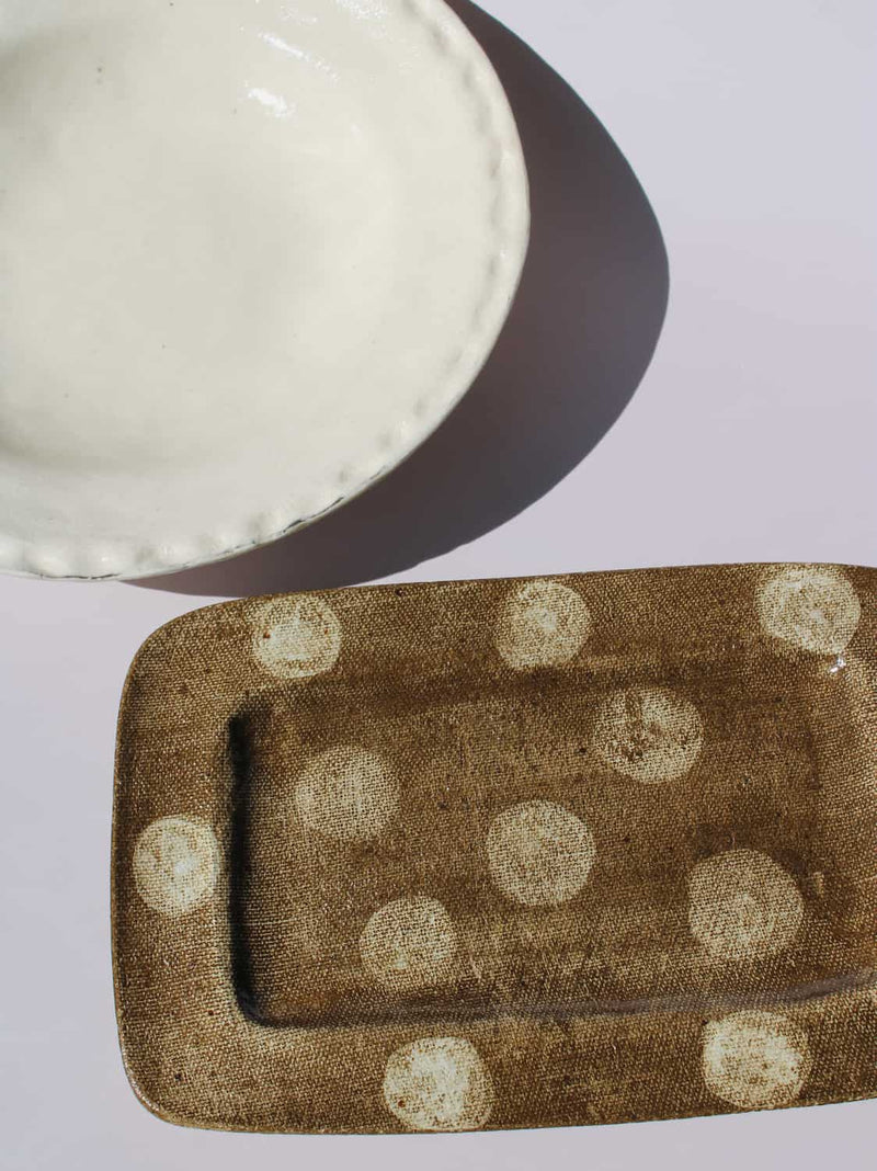 Lunette Ceramic Plate paired with Biscotti Ceramic Plate, cream scalloped plate beside brown polka dot rectangular tray