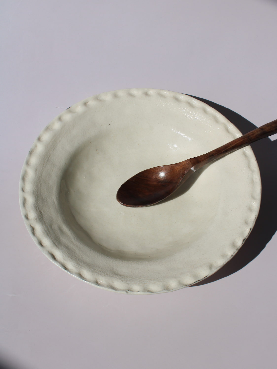 Lunette Ceramic Plate with scalloped beaded edge, styled with a wooden fork, handmade ceramic plate top view