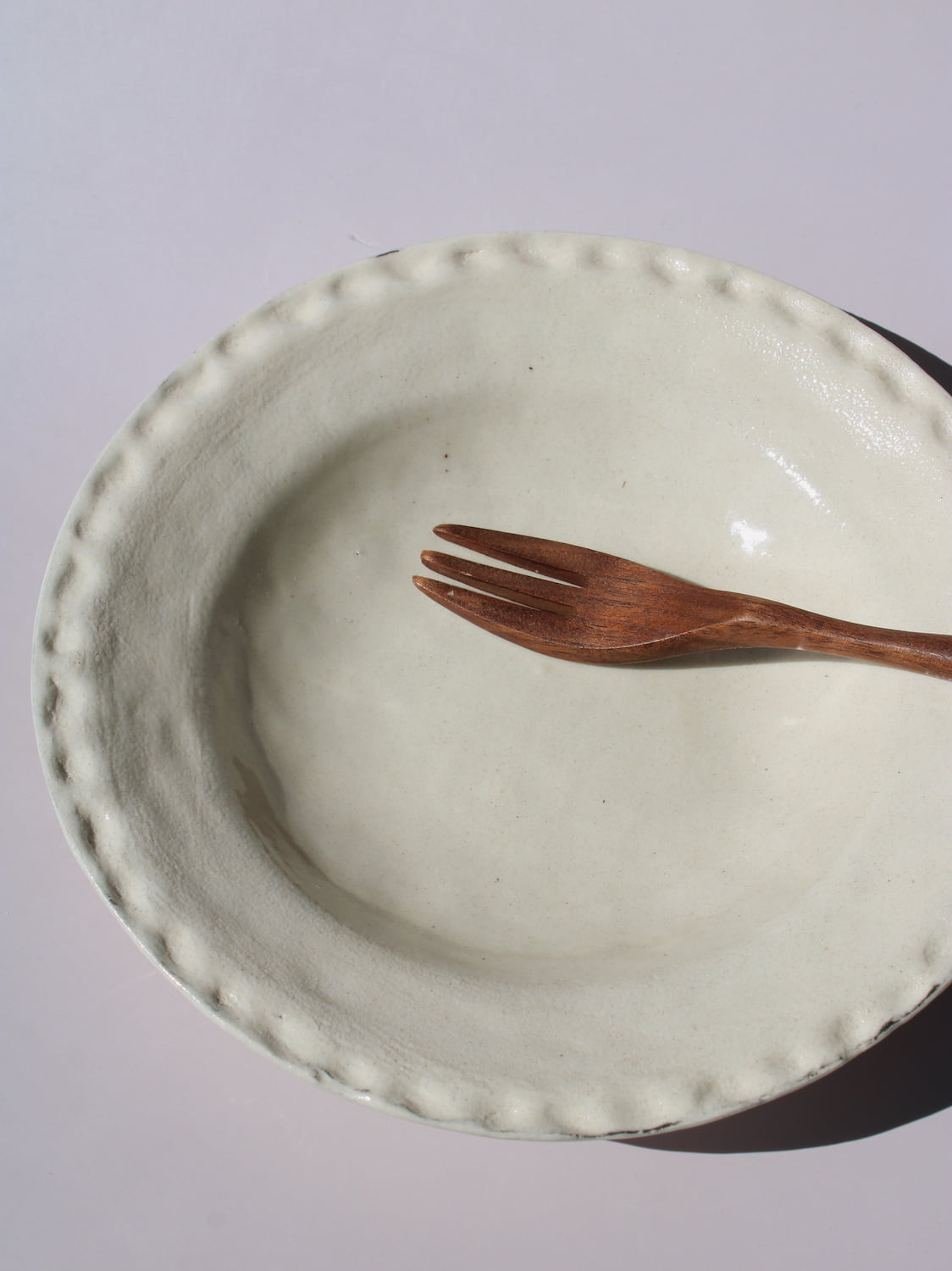 Lunette Ceramic Plate with scalloped beaded edge, styled with a wooden fork, handmade ceramic plate top view