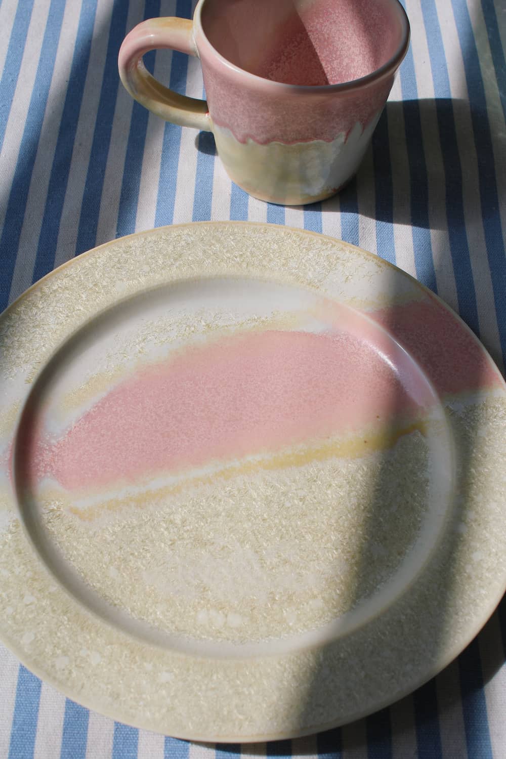 Aurora ceramic plate with soft pink glaze and textured beige rim, modern handmade dinnerware.