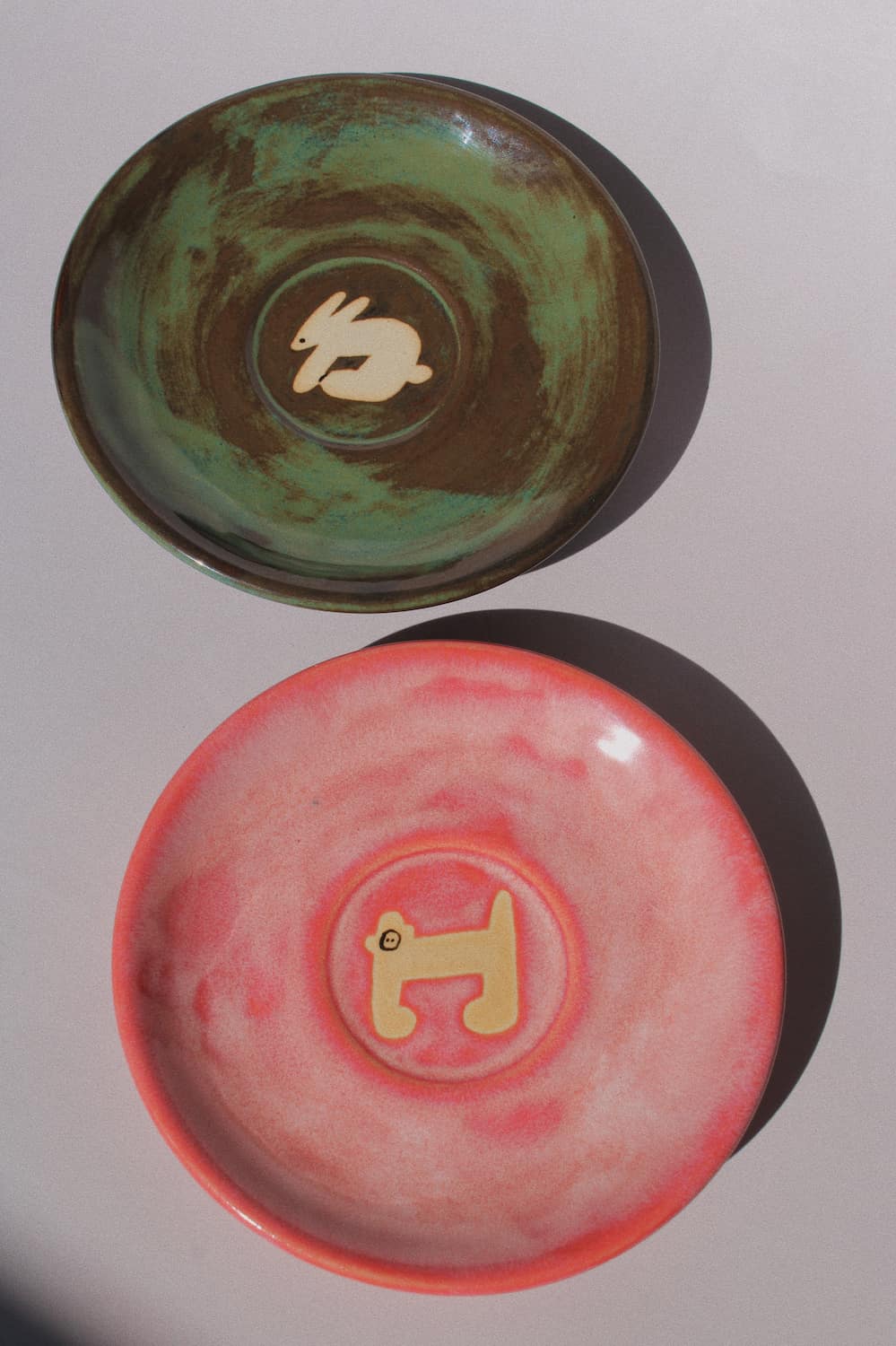 Woodland Rabbit and Candy Monkey Ceramic Plates by Marta Shurpakova – handmade illustrated ceramic plates in earthy green and playful pink tones