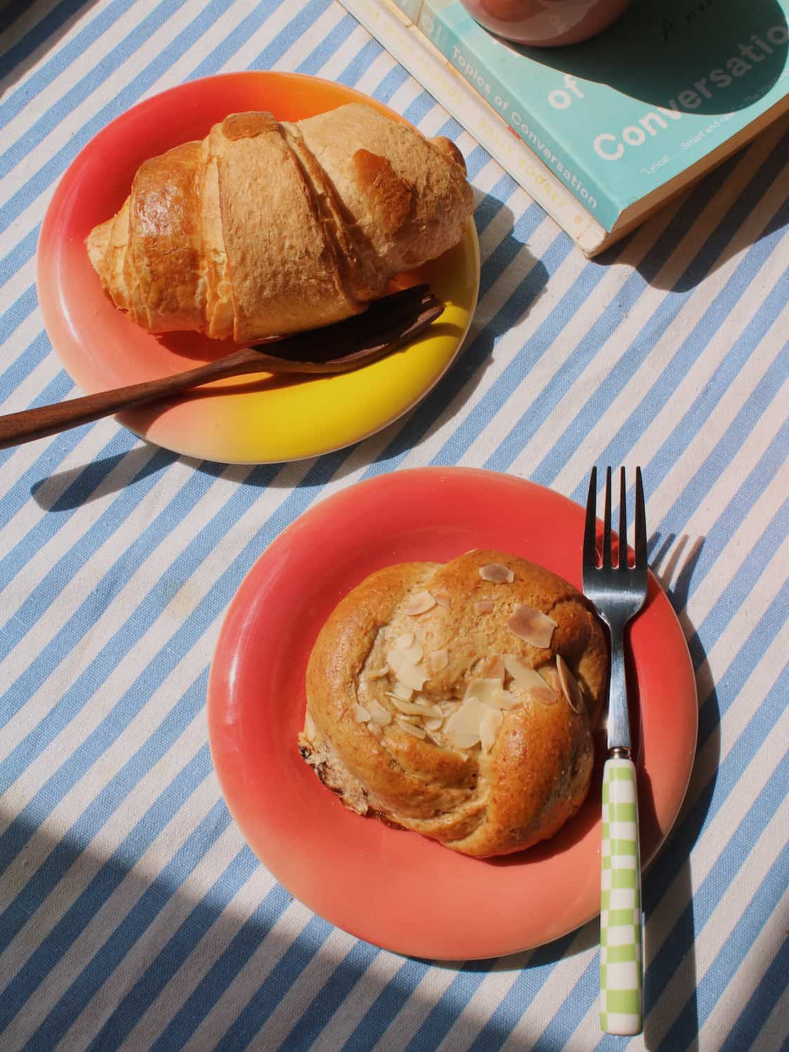 Belly Poppy Ceramic Plate by Agata Puławska – colourful handmade ceramic plate styled with a pastry and wooden fork on a blue striped tablecloth