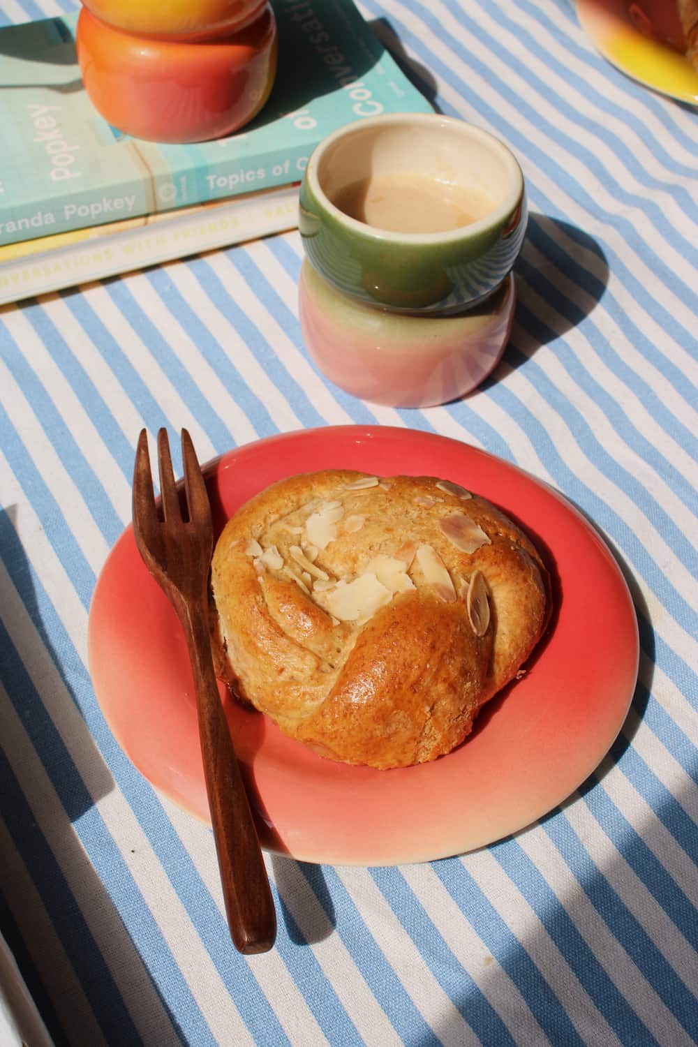Belly Poppy Ceramic Plate by Agata Puławska – colourful handmade ceramic plate styled with a pastry and wooden fork on a blue striped tablecloth