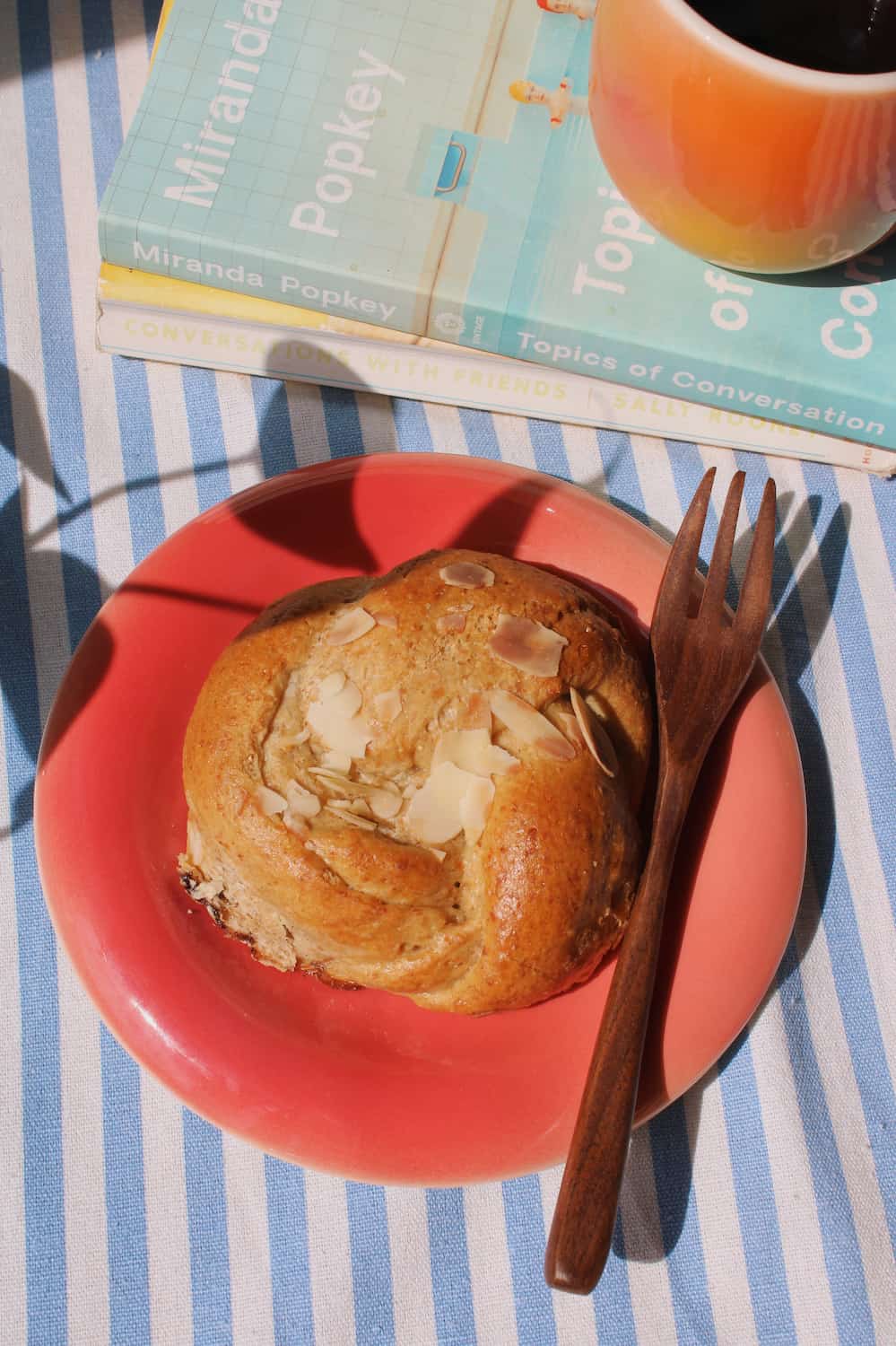 Belly Poppy Ceramic Plate by Agata Puławska – colourful handmade ceramic plate styled with a pastry and wooden fork on a blue striped tablecloth