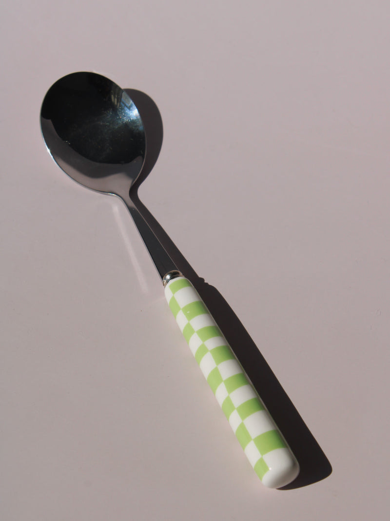 Nico Fork and Spoon Set in stainless steel with green and white checkered handles, on a soft pink background.