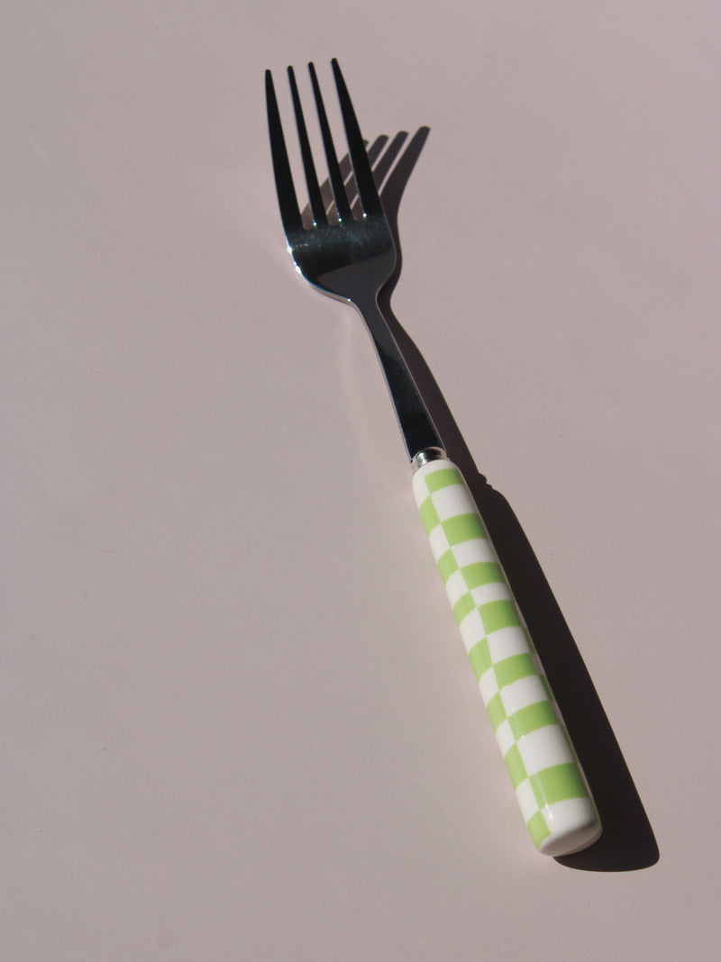 Nico Fork and Spoon Set in stainless steel with green and white checkered handles, on a soft pink background.