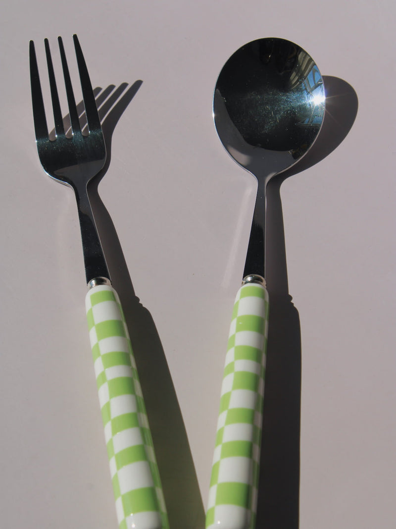 Nico Fork and Spoon Set in stainless steel with green and white checkered handles, on a soft pink background.
