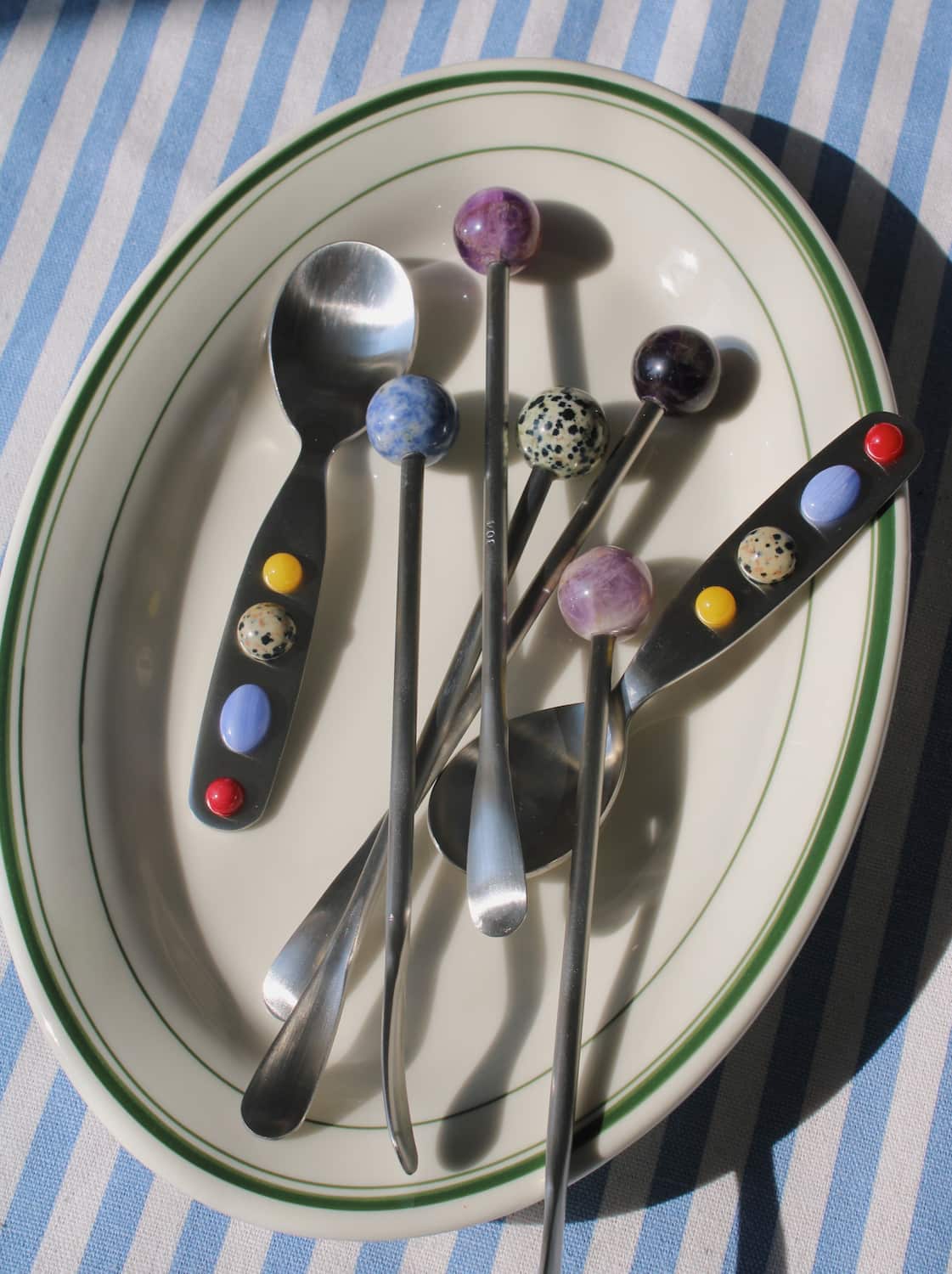 Set of Constella spoons with colorful bead handles arranged on plate.