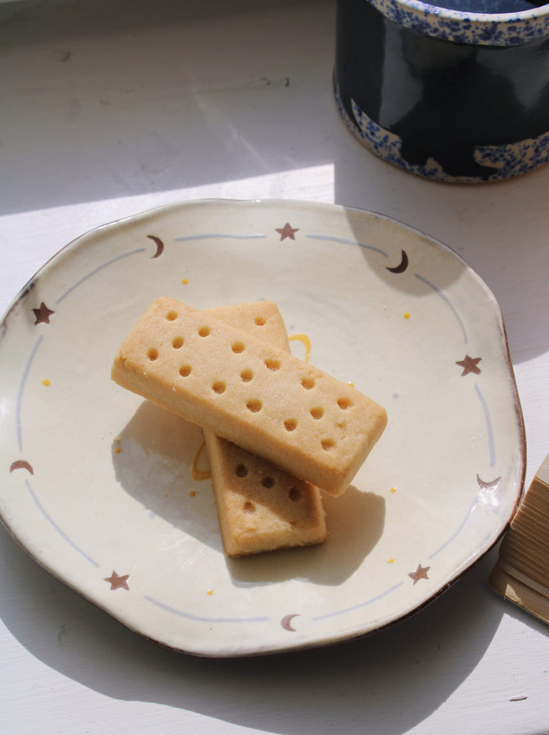 Elio ceramic plate with biscuit snack in soft natural light on minimal table setting.
