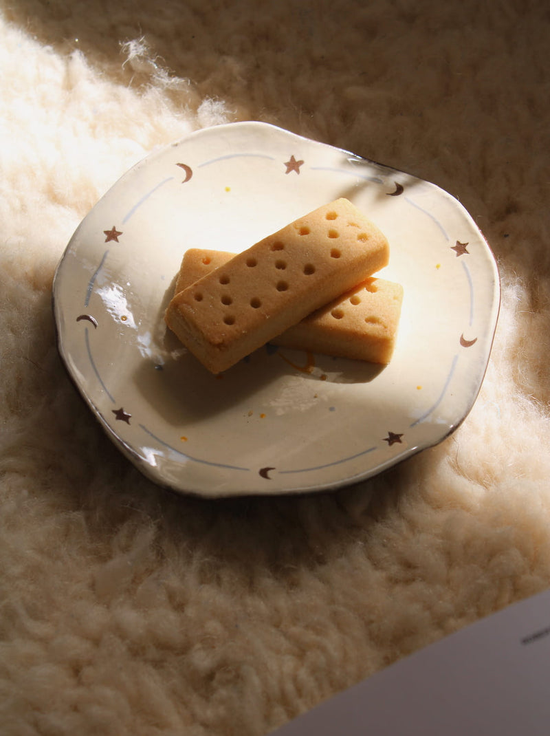 Elio ceramic plate with pastry in warm sunlight creating soft shadows.