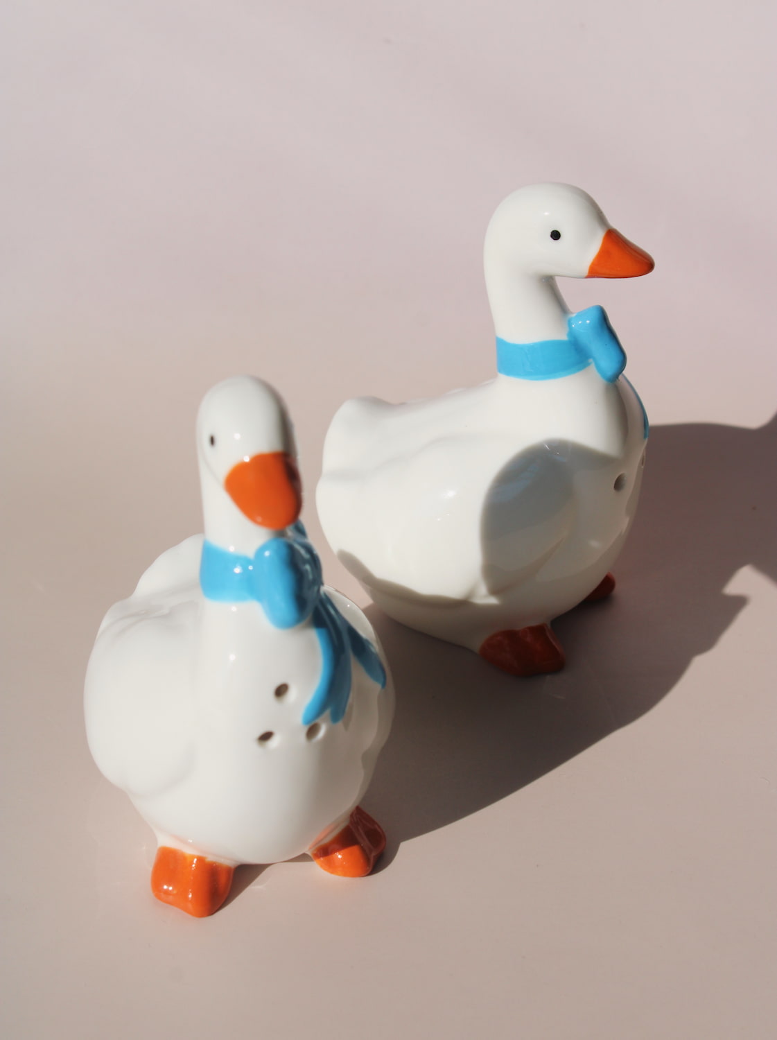 Ceramic duck salt and pepper shakers with blue scarves and orange beaks in glossy finish.