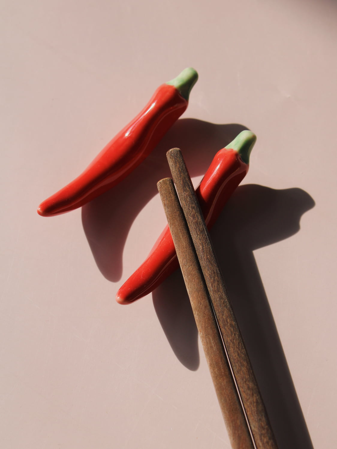 Chili Ceramic Chopstick Rest Set in red chili pepper shape with green stem, styled with a wooden fork, handmade ceramic