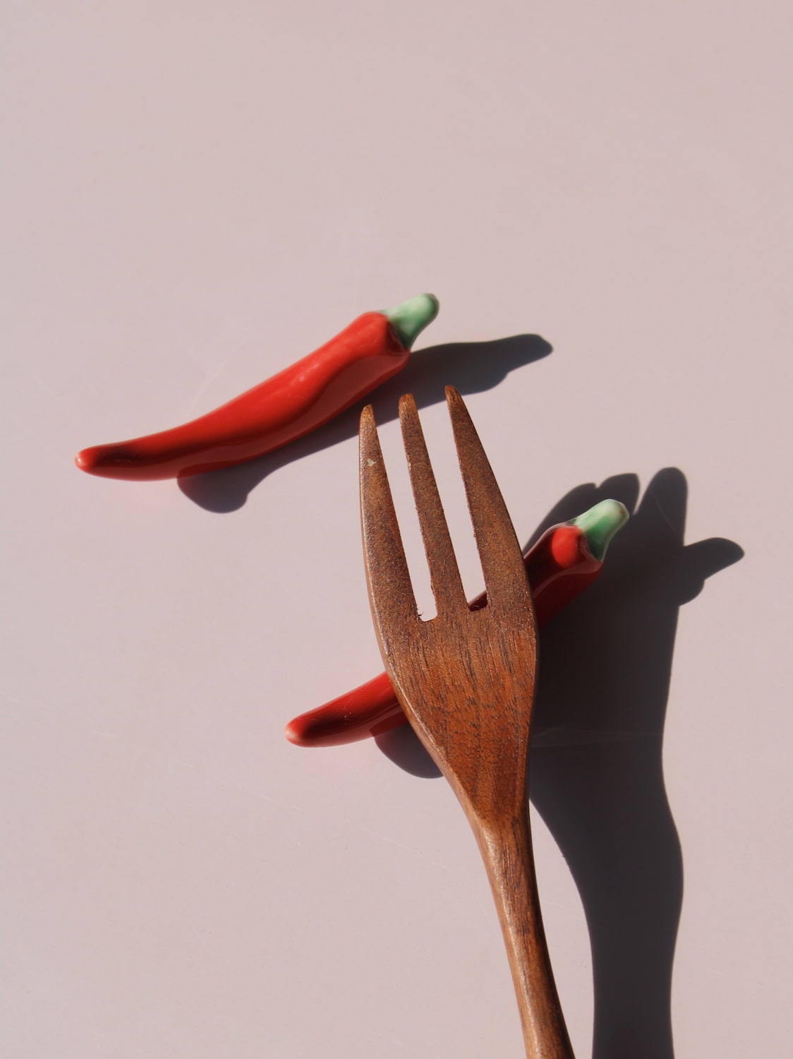 Chili Ceramic Chopstick Rest Set in red chili pepper shape with green stem, styled with a wooden fork, handmade ceramic
