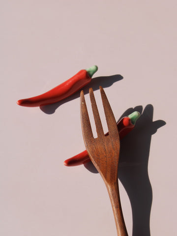 Chili Ceramic Chopstick Rest Set in red chili pepper shape with green stem, styled with a wooden fork, handmade ceramic