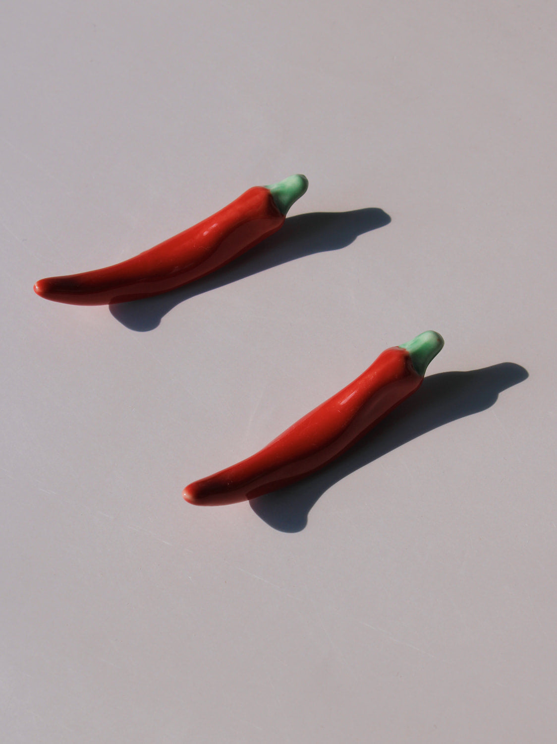 Chili Ceramic Chopstick Rest Set in red chili pepper shape with green stem, styled with a wooden fork, handmade ceramic