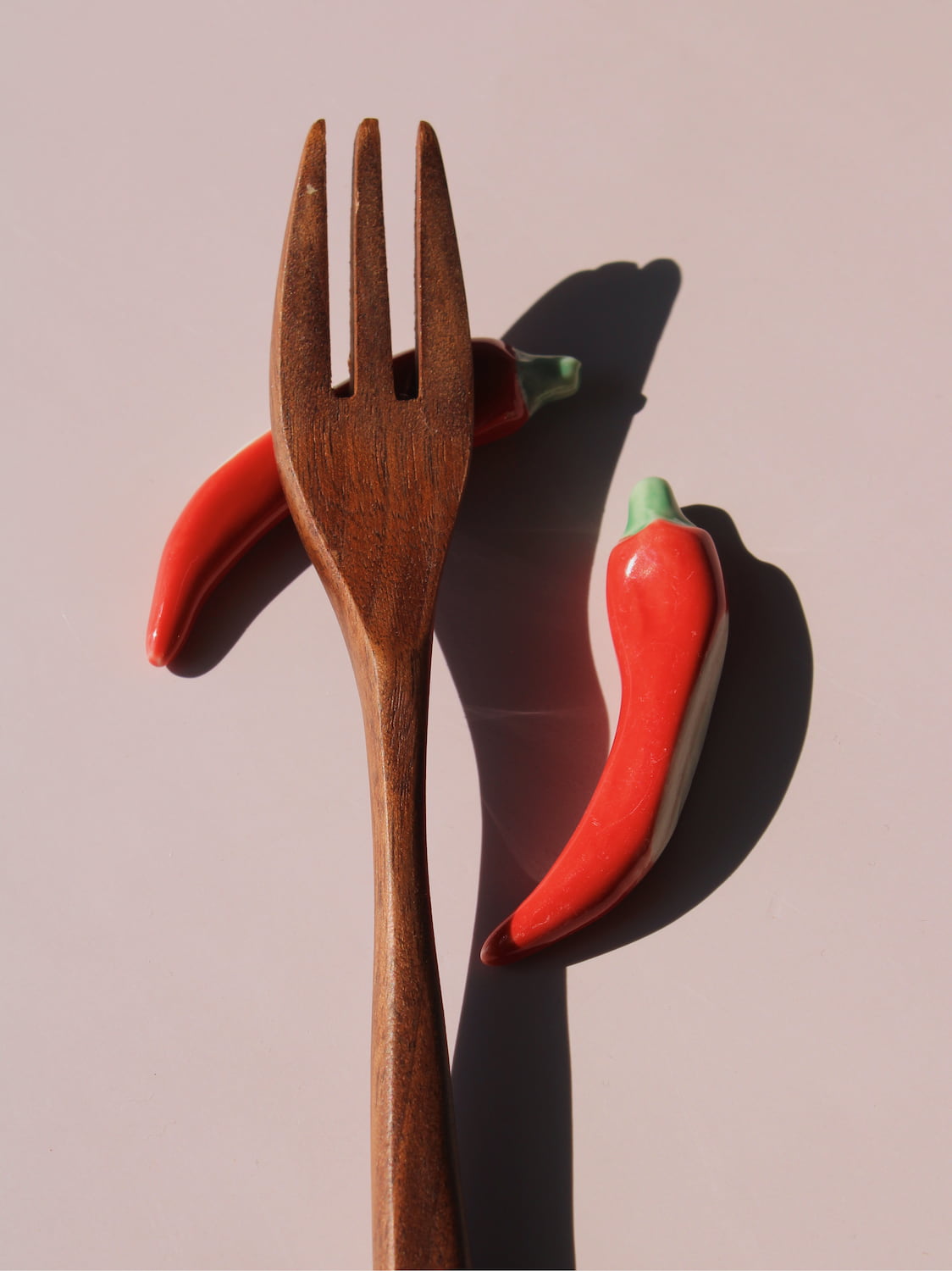 Chili Ceramic Chopstick Rest Set in red chili pepper shape with green stem, styled with a wooden fork, handmade ceramic