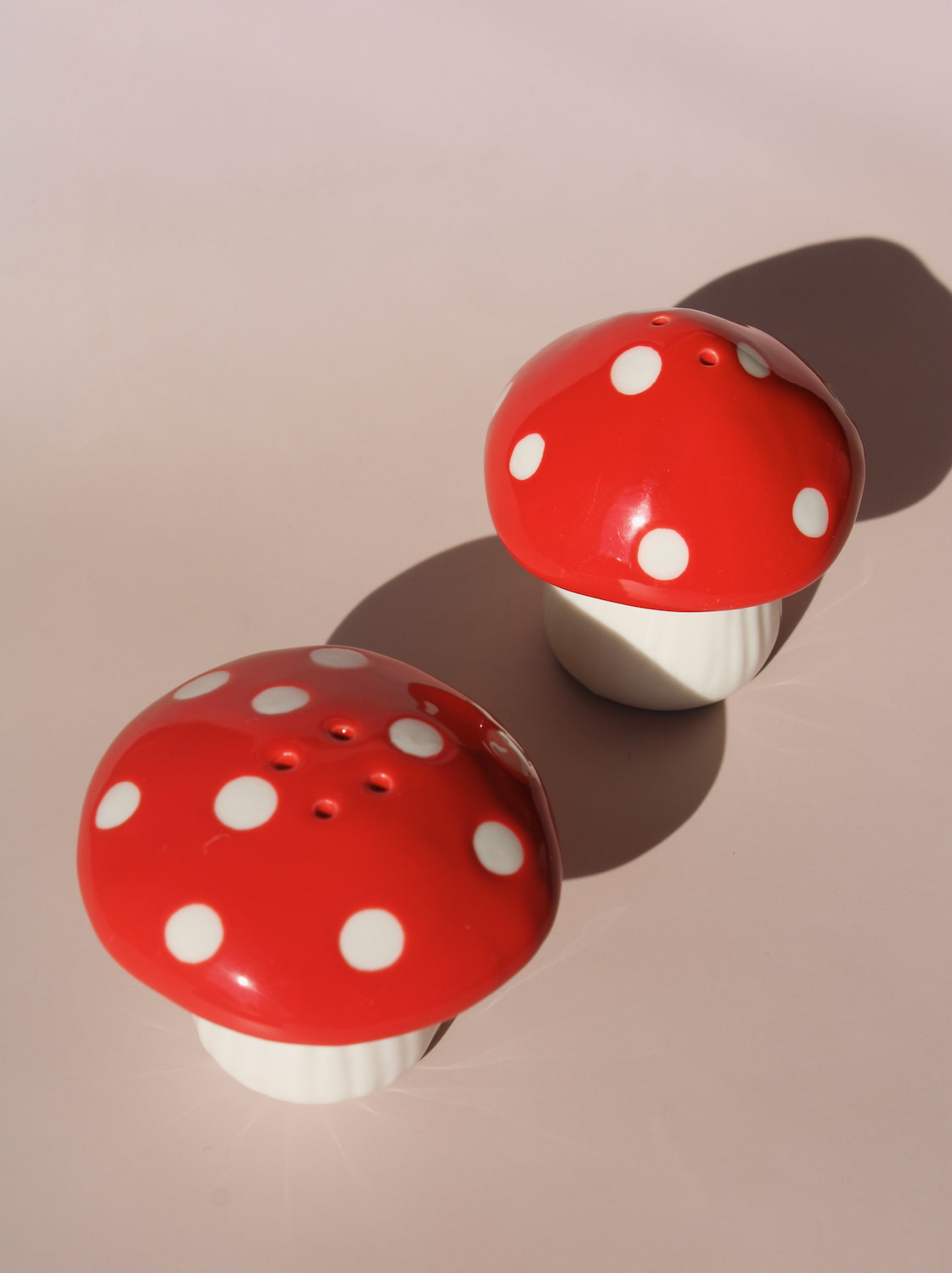 Red mushroom salt and pepper shakers with white polka dots in glossy ceramic finish.