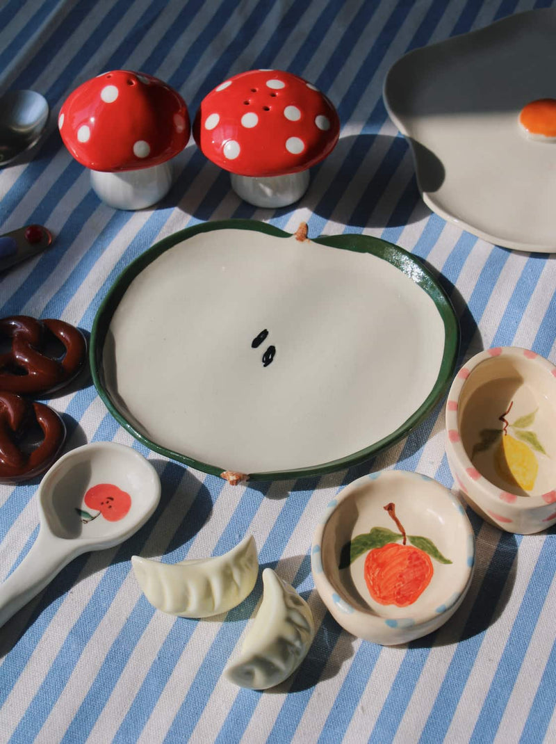 Collection of ceramic items including a plate, bowls, and containers on a striped tablecloth.