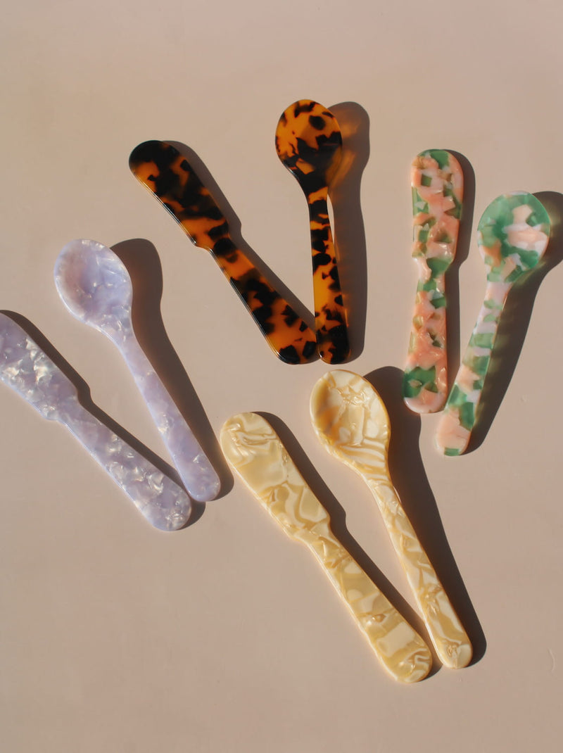 Colorful marbled resin spoons in tortoiseshell, lavender, green, and cream acrylic designs.