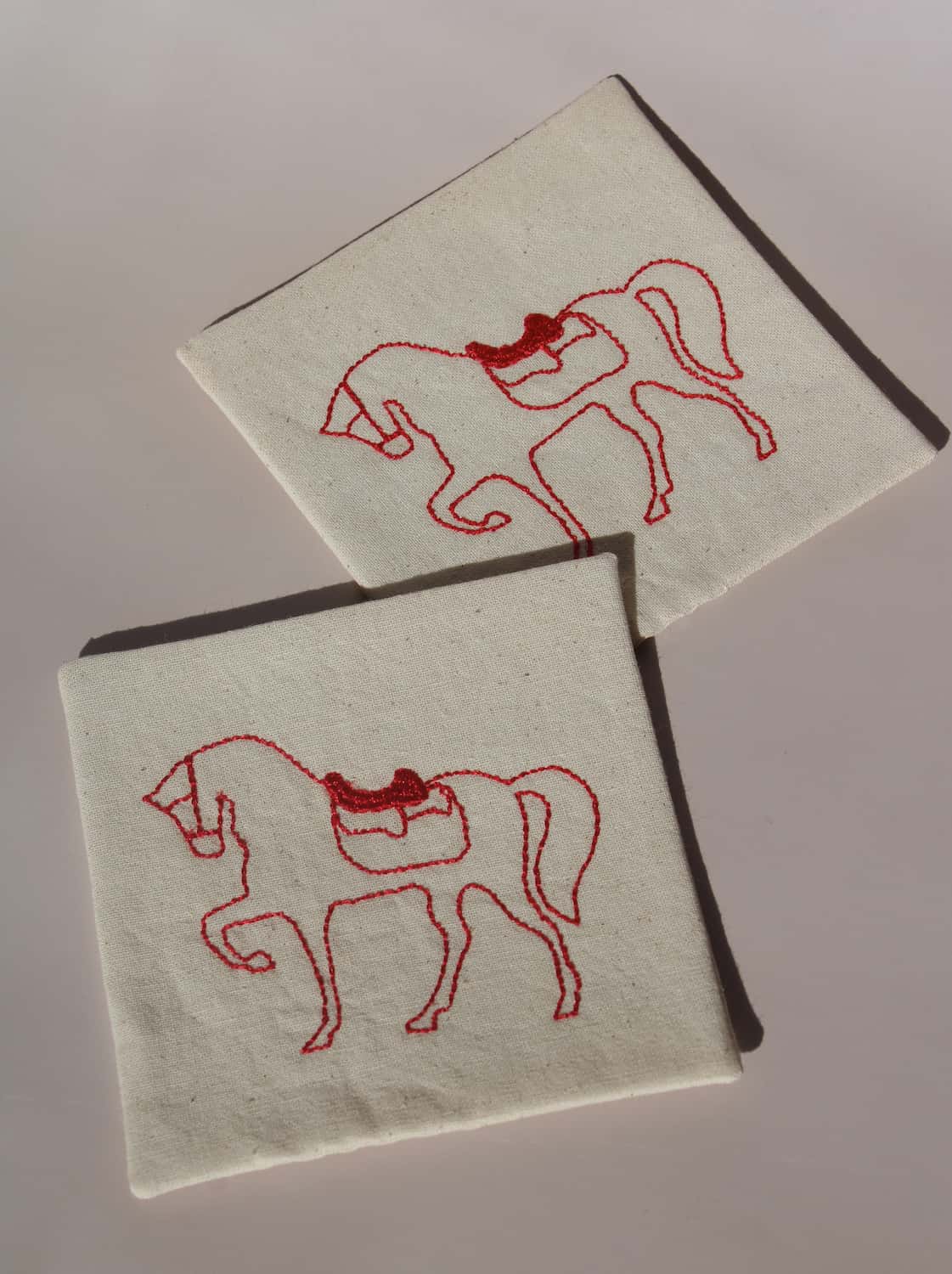 Cavalier Handsewn Embroidered Coaster with red horse design on natural cotton fabric, handmade textile drink coaster.