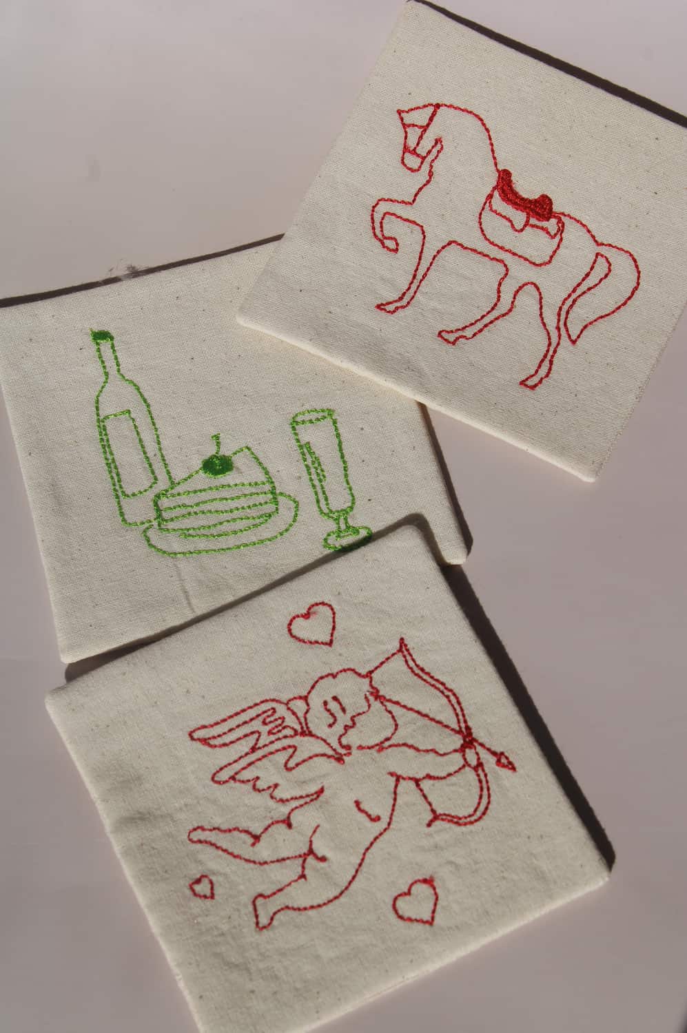 Maison Handsewn Embroidered Coaster with wine motif and Amour Handsewn Embroidered Coaster with cupid embroidery styled together on table.